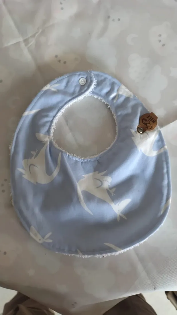 Babero celeste con ballenas blancas y broche